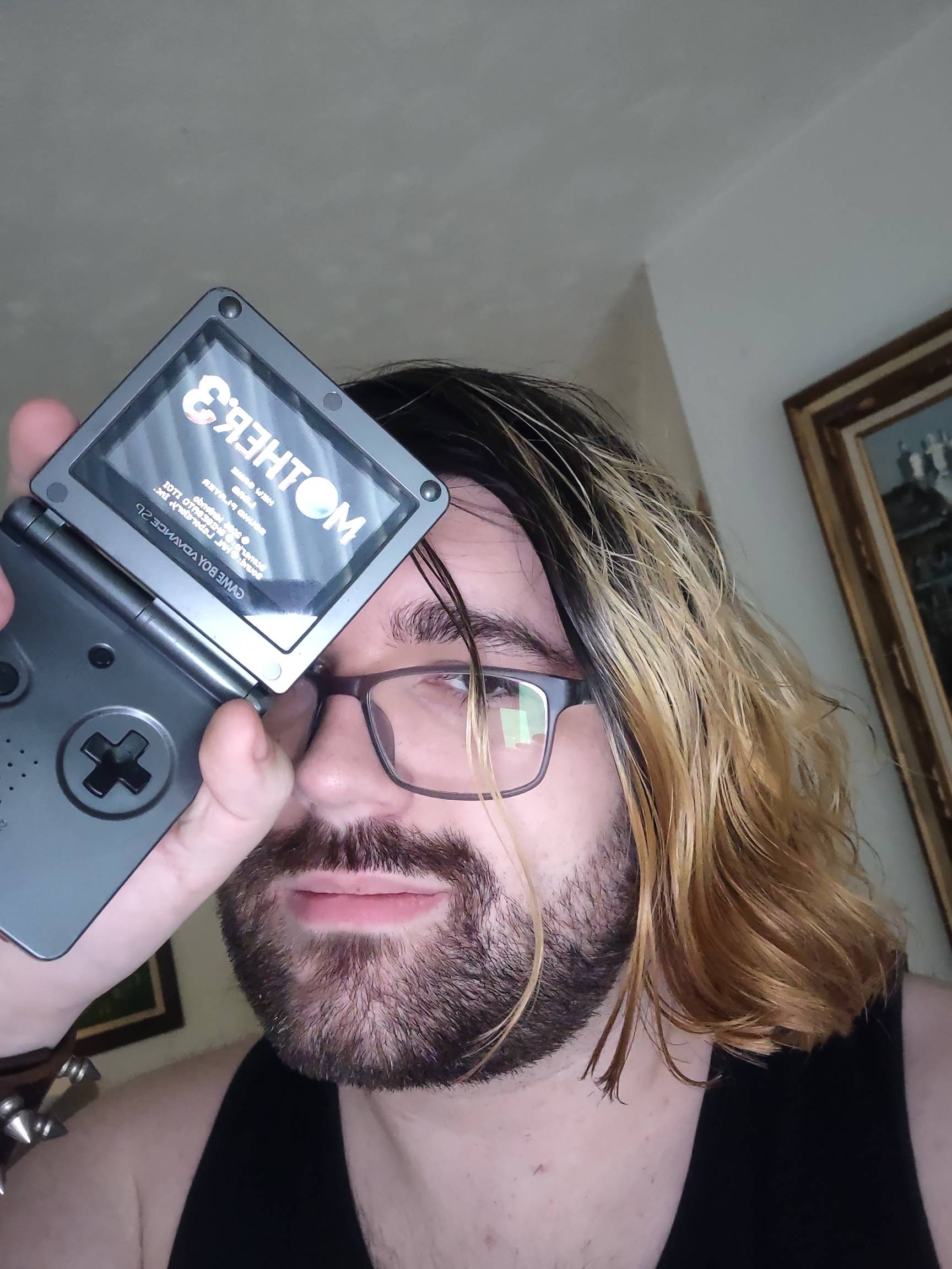 a selfie taken of myself, holding up a gameboy advance playing mother 3