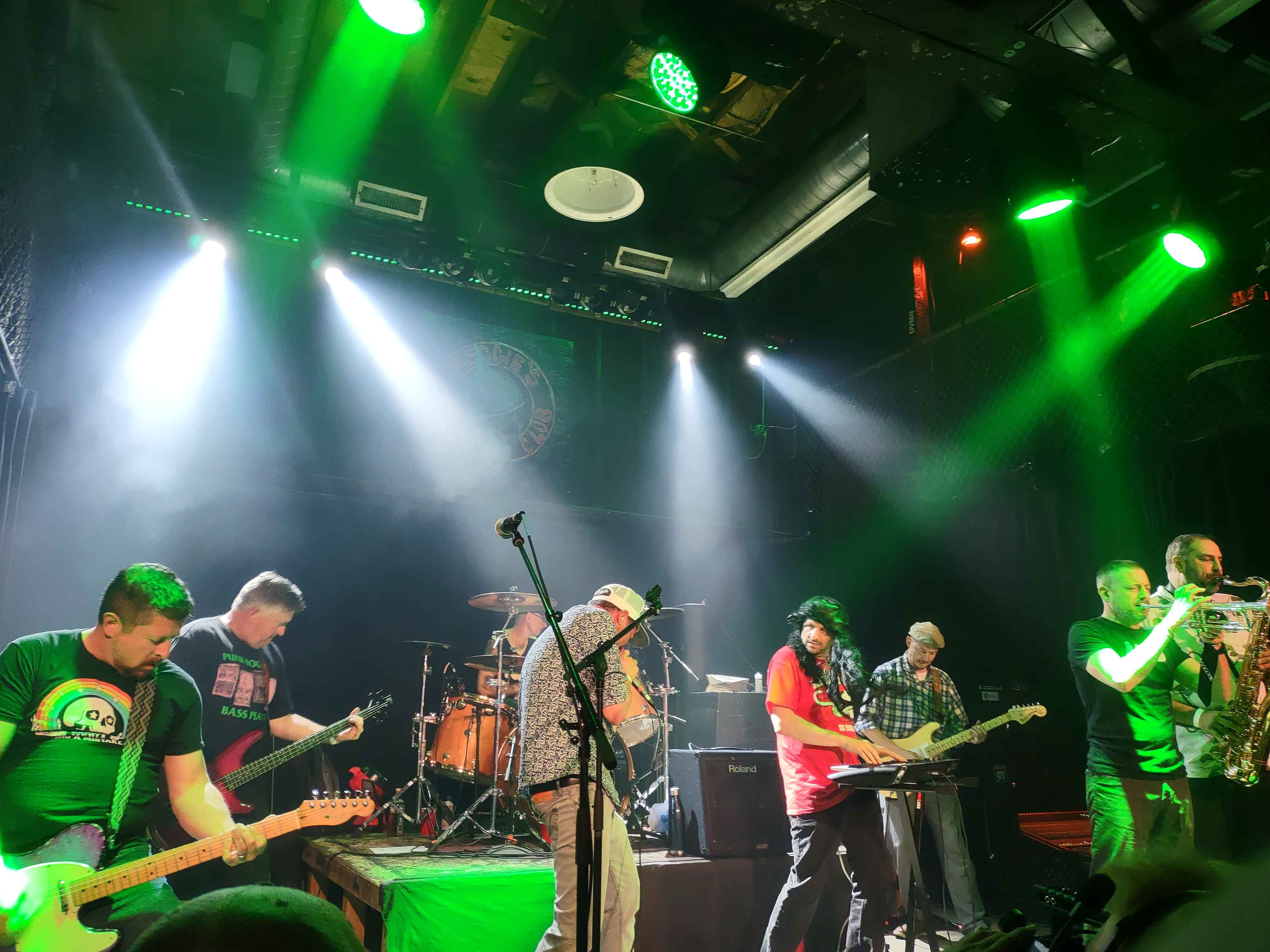 a photo taken of an 8 piece ska band under green and white stage lights.